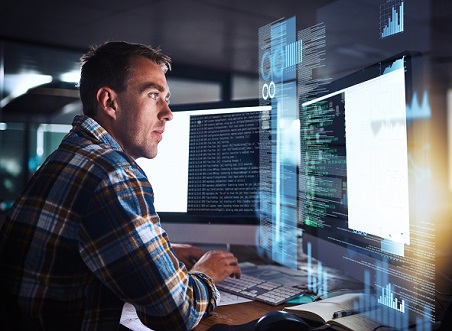 A man programming and reading computer codes on large computer monitors