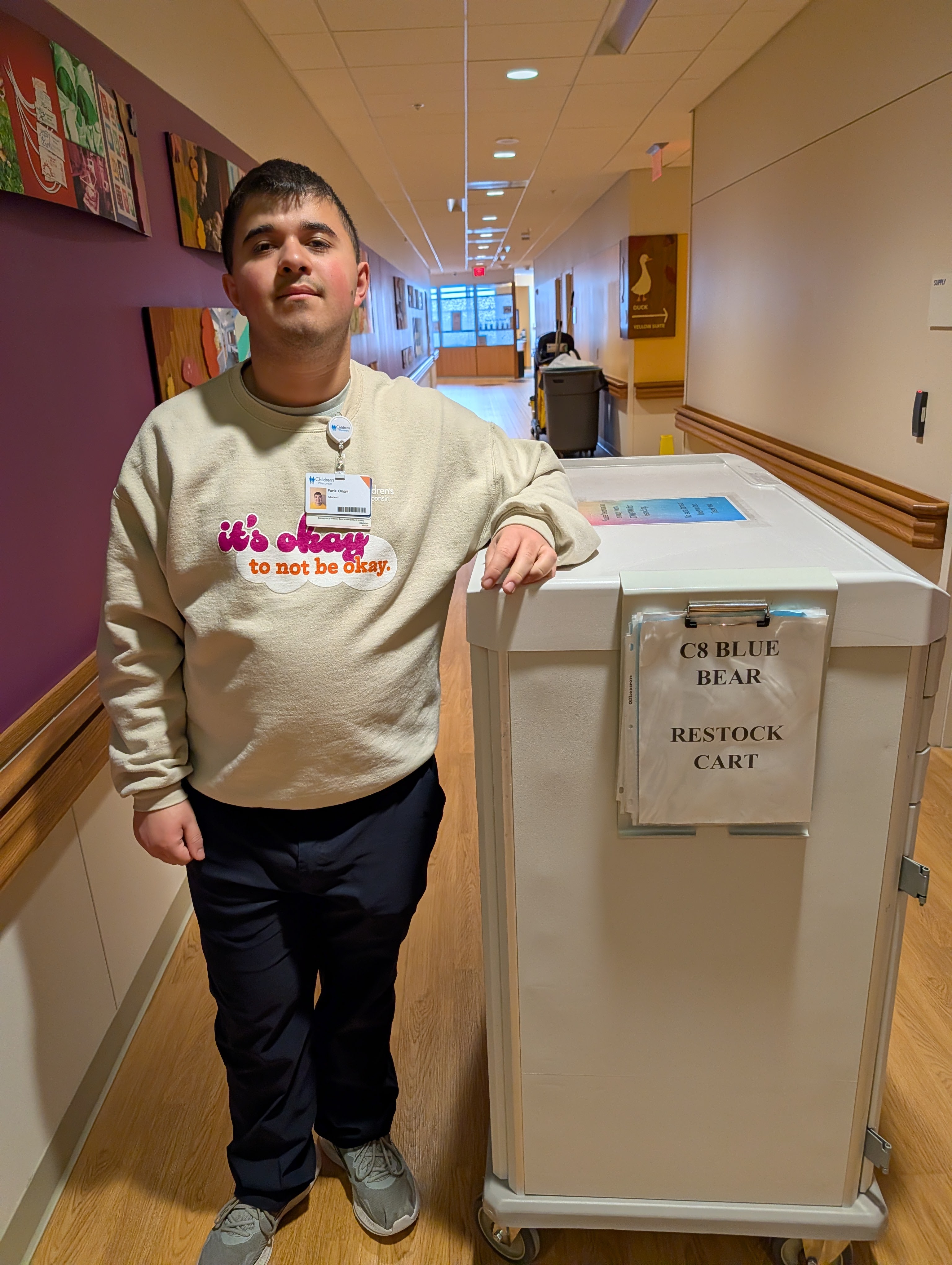 Faris stands proudly next to a supply restocking cart
